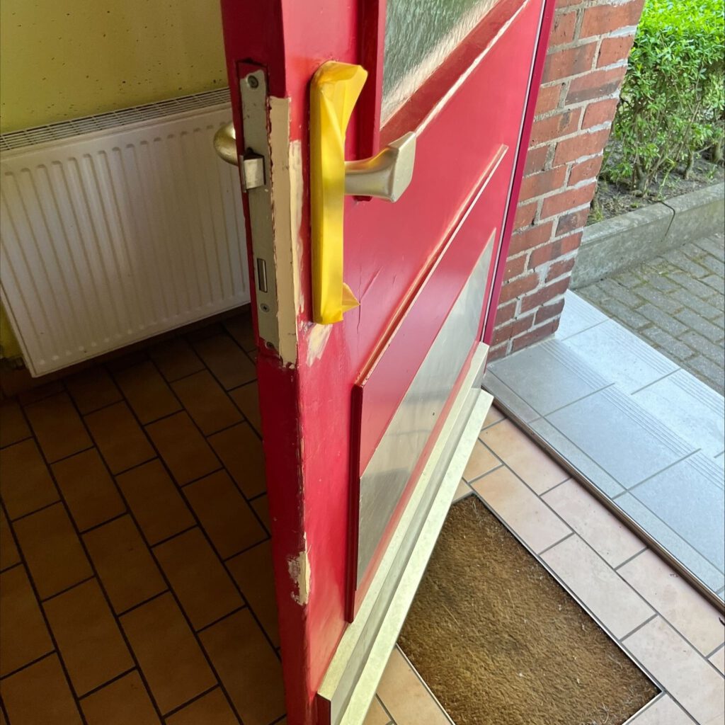 Einbruchschaden an Haustür mit Kratzern und Hebelspuren am Türschloss