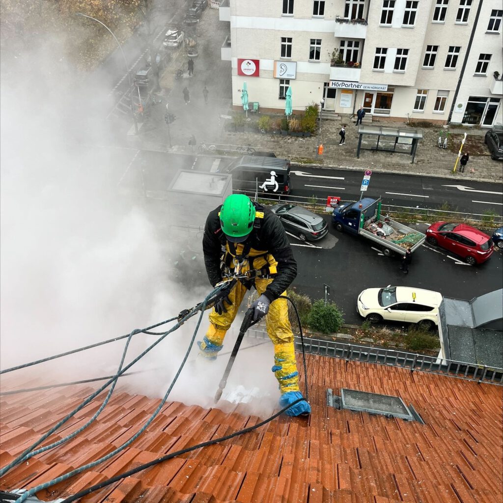 Industriekletterer bei Graffitientfernung auf Berliner Altbaudach mit Seiltechnik